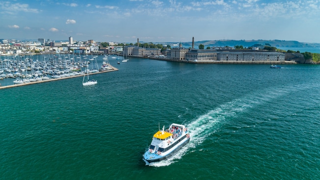 Un bote lleno de personas navega por un muelle y una ciudad costera Un bote lleno de personas navega por un muelle y una ciudad costera