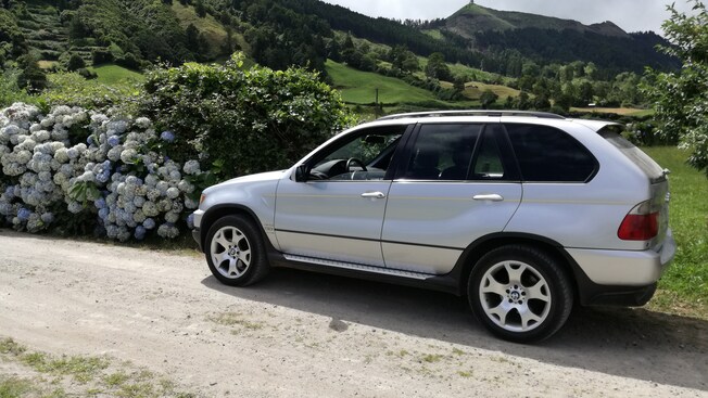 A late model BMW SUV on a dirt road in the countryside