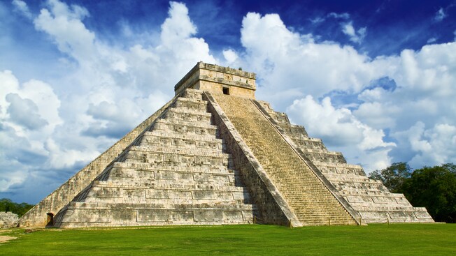 An ancient Mayan pyramid with grass and trees