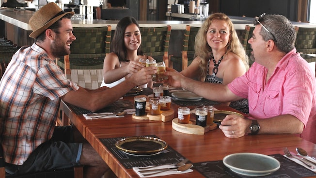 4 people sit at a table and toast beer samples from individual beer flights 4 people sit at a table and toast beer samples from individual beer flights