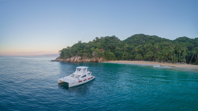 A catamaran docked near the shore of a secluded beach
