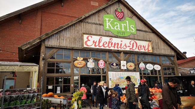 Guests outside a small market with a sign that reads Karls 1921 Guests outside a small market with a sign that reads Karls 1921