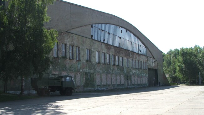 A vintage military truck parked outside of a vintage hangar