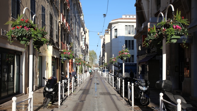 Historic homes, shops and flower baskets lining a narrow street
