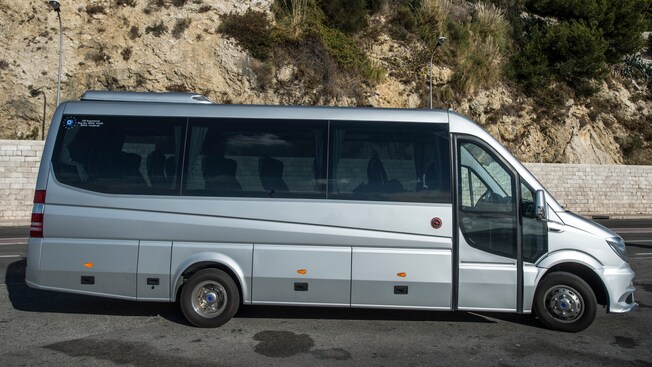 A late model minibus parked near a hillside