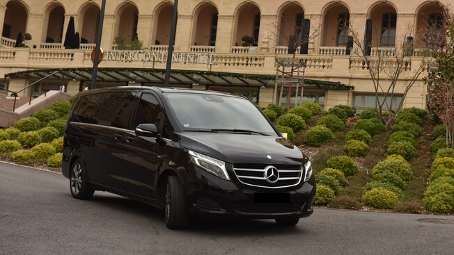A late model minivan parked in front of a luxury hotel
