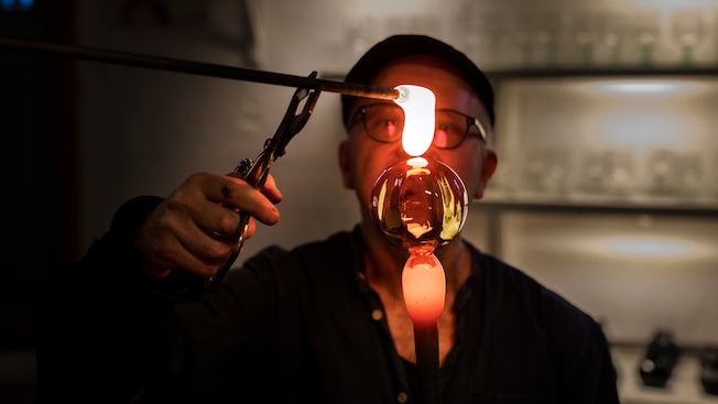 A glassblower working with a rod containing a molten glass bubble