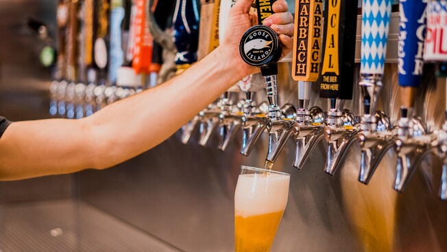 Un camarero tira hacia abajo una palanca para servir una copa de cerveza