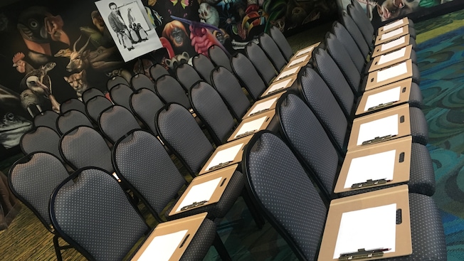A picture of Walt Disney with penguins behind an array of chairs and art clipboards