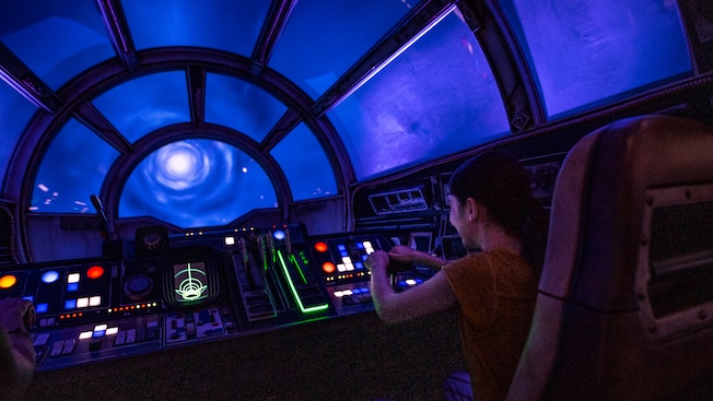 A young pilot sits in the cockpit of the Millennium Falcon while traveling through hyperspace