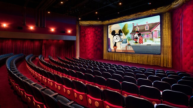 An empty theater with a film featuring Mickey and Minnie Mouse projected on the movie screen