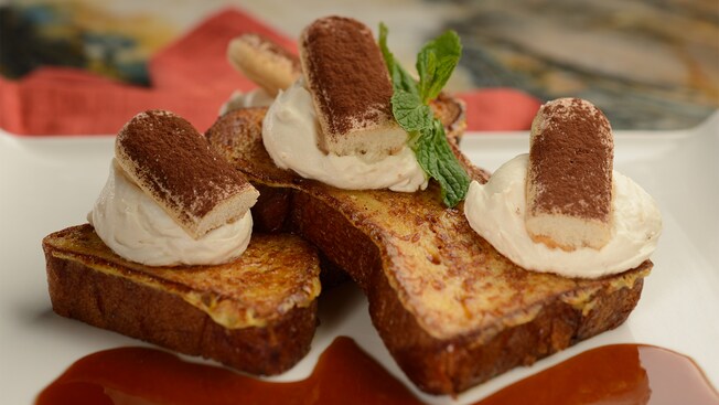 French toast topped with tiramisu and an herb leaf, served with a dipping sauce