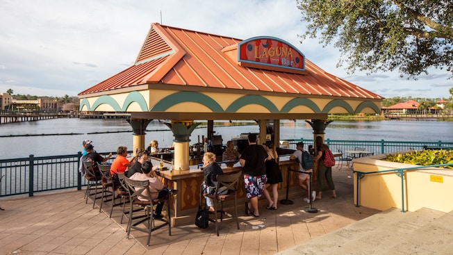 Guests lounging around a walk-up bar located near a body of water
