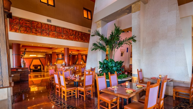 A restaurant dining area featuring high ceilings, plants and contemporary Mexican decor