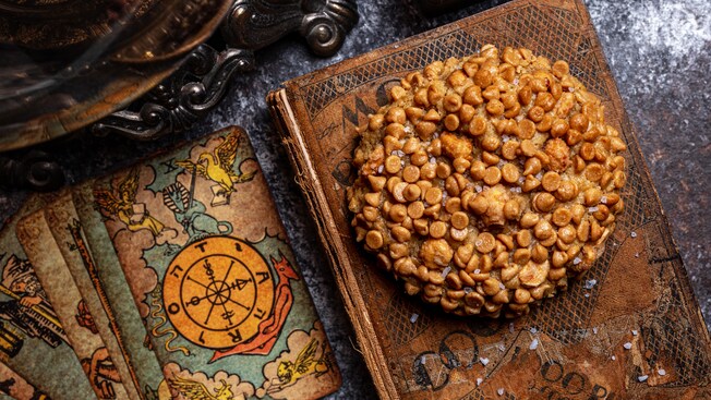 A Peanut Butter Cookie on an old cookbook surrounded by tarot cards