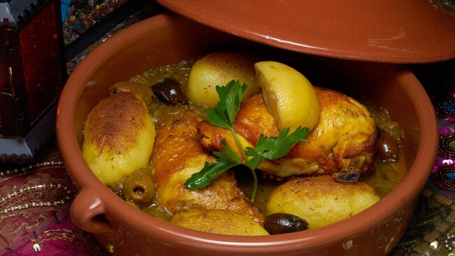 Half chickens served in a tagine with lemon wedges and olives