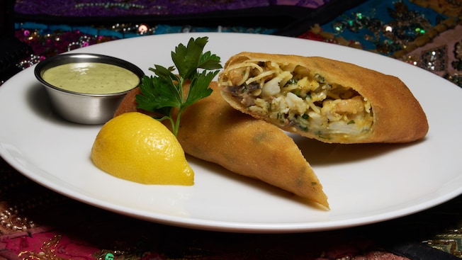 2 thin pastries, filled with seafood and mushrooms, served with a cup of sauce and a lemon wedge