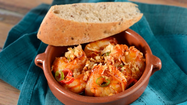 A bowl of garlic shrimp with a slice of bread