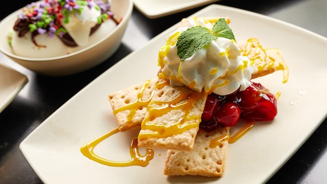 A dessert of stacked cookies with caramel, whipped cream and mint