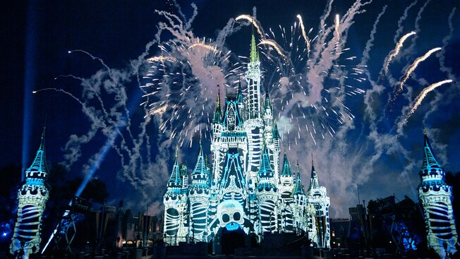 Skeleton bones are projected on Cinderella Castle as fireworks light up the night sky