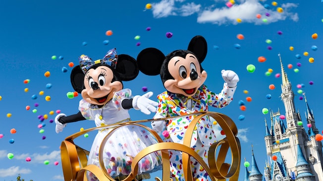 Confetti flies around Mickey Mouse and Minnie clad in party outfits with a confetti pattern