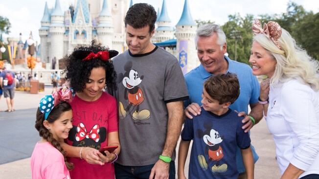 A family looks at a cell phone near Cinderella Castle