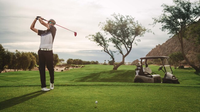 Un golfista con gafas de sol hace un swing con su palo en un campo de golf