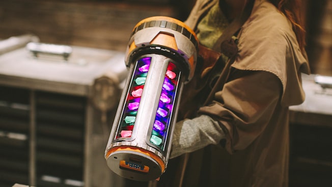 A Savi Gatherer holds a huge vial containing luminescent kyber crystals