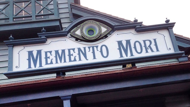 A sign that reads 'Memento Mori' on the front of a building