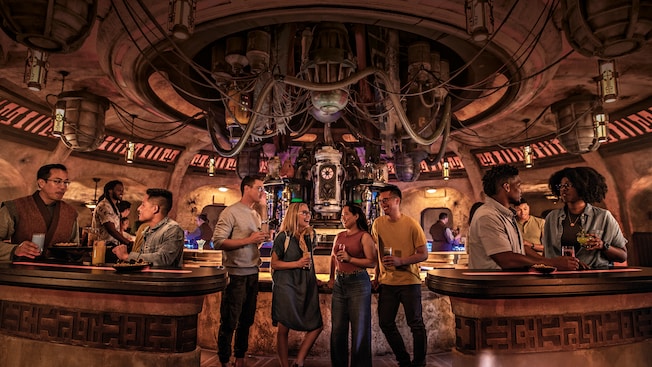 Adults enjoy exotic beverages inside a Star Wars cantina with hoses, tubes and unusual machines