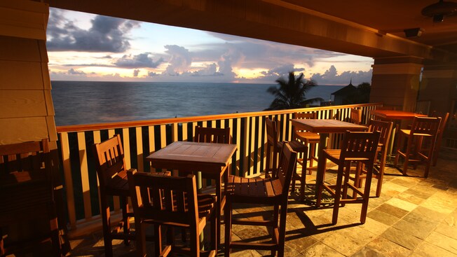 High tables and chairs on the patio overlook the ocean below