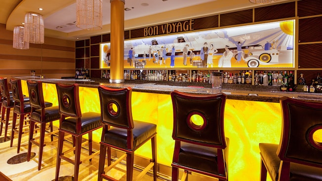 El Bon Voyage Bar tiene un mural de arte sobre la barra y taburetes con respaldo alto El Bon Voyage Bar tiene un mural de arte sobre la barra y taburetes con respaldo alto