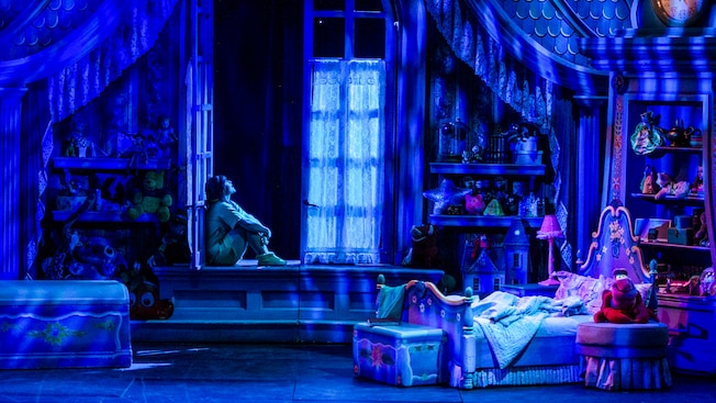 A young girl sits in her open bedroom window at night, imagining the magic of dreams. A young girl sits in her open bedroom window at night, imagining the magic of dreams.