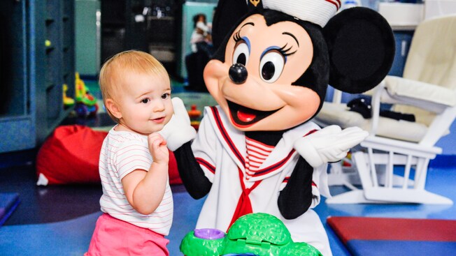 On the Disney Wonder at Flounders Reef Nursery, a little girls stands next to Minnie Mouse