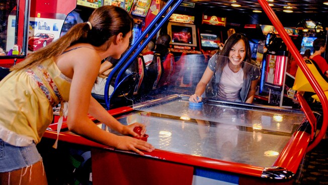 Two girls play a game of air hockey in the Quarter Masters arcade on the Disney Magic