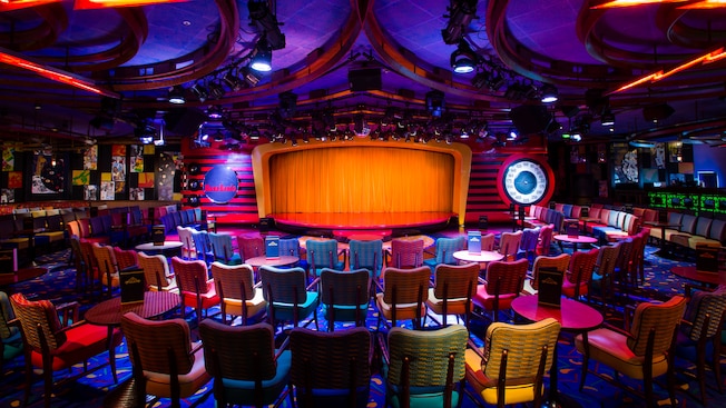 A nightclub has lots of chairs and tables facing a dance floor area A nightclub has lots of chairs and tables facing a dance floor area