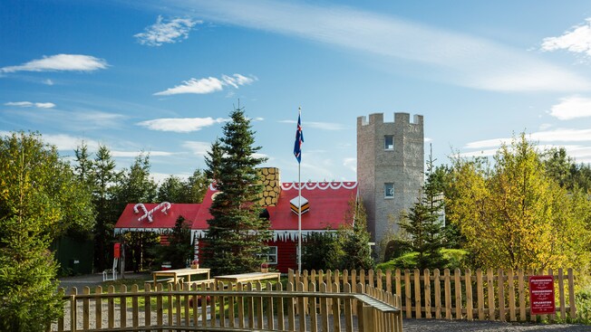 A Christmas themed house embellished with candy canes on the roof and a medieval looking tower
