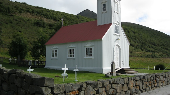 A small wooden chapel surrounded by greenery A small wooden chapel surrounded by greenery