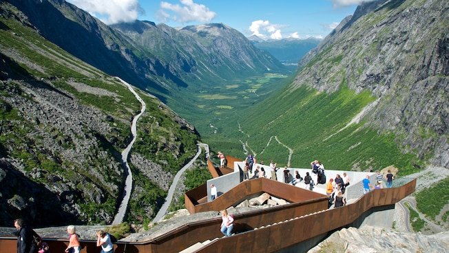 An observation deck looks out to a highway zigzagging across a verdant valley