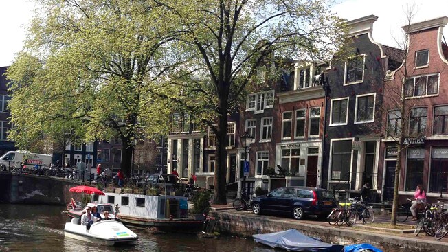 Amsterdam & Canal Bike Pedal BoatA young family of 4 glides through an Amsterdam canal in a small pedal boat