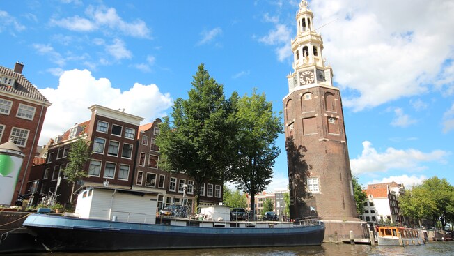 Uma casa flutuante atracada próximo à Clock Tower em Amsterdã Uma casa flutuante atracada próximo à Clock Tower em Amsterdã