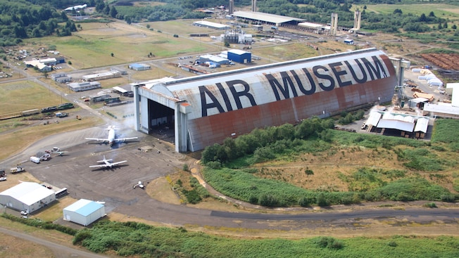 Airplanes and a large hanger near outlying buildings Airplanes and a large hanger near outlying buildings