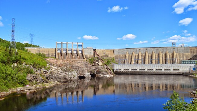 Uma barragem hidrelétrica, próxima a um corpo d’água e de árvores
