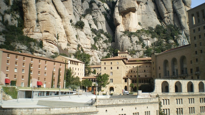 Stone buildings stand in front of Montserrats rocky mountains