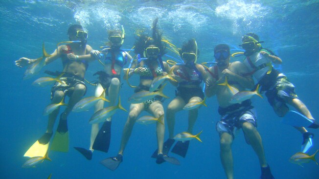 A family links arms underwater to pose in Snuba gear