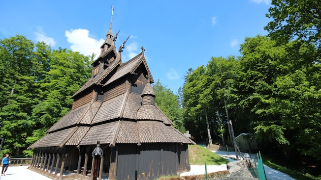 A medieval stave church next to bushy trees A medieval stave church next to bushy trees