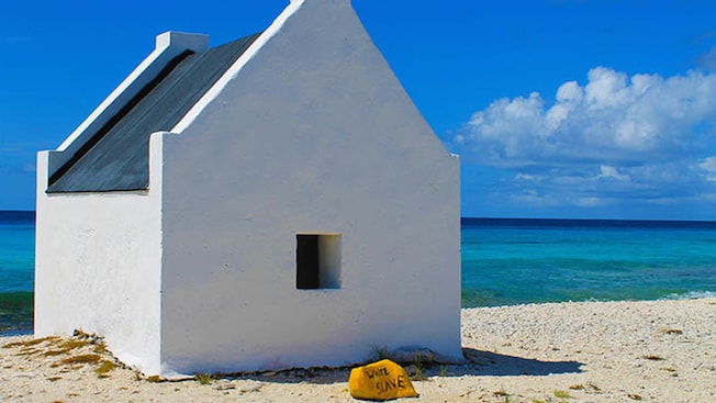 Una cabaña en la playa cerca de una roca con las palabras “White Slave” (Esclavo Blanco) Una cabaña en la playa cerca de una roca con las palabras “White Slave” (Esclavo Blanco)