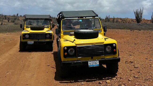 2 Land Rovers driving through a rocky desert