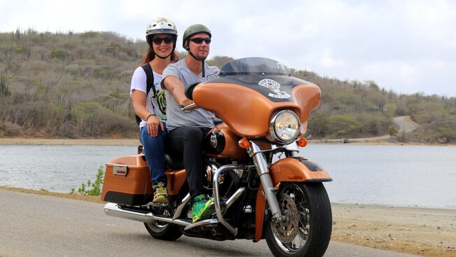 A couple rides a Harley Davidson motorcycle