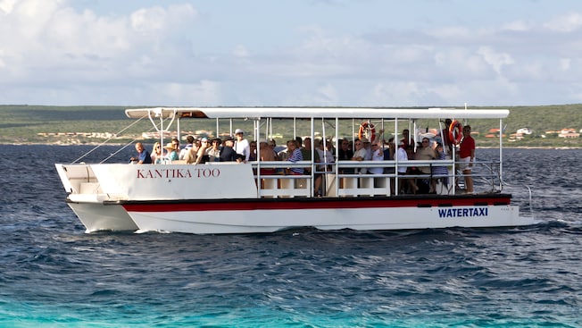 A water taxi full of people floats across a bay A water taxi full of people floats across a bay